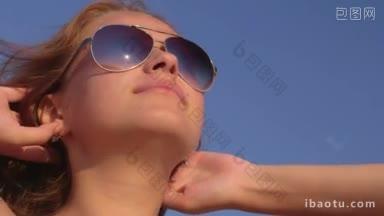 年轻女孩的脸戴着太阳镜在海滩上<strong>晒太阳</strong>